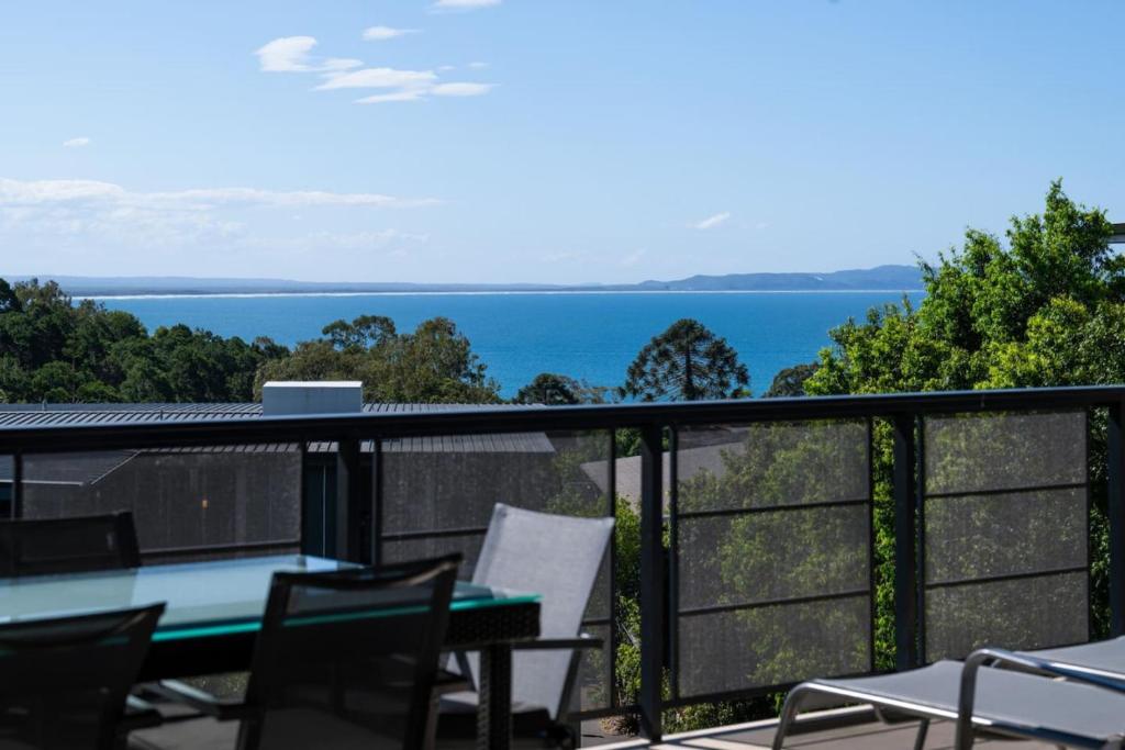 a balcony with a table and chairs and the ocean at Panoramic Ocean Penthouse in Noosa Heads