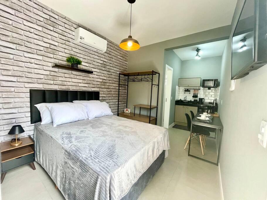 a bedroom with a bed and a brick wall at Loft Studio 101 em São José à 7km de Floripa in São José