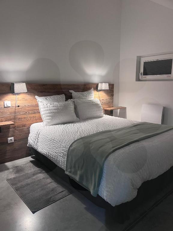 une chambre avec un grand lit avec des draps et des oreillers blancs dans l'établissement Gites L'atelier 1410, à Saint-Amand-les-Eaux