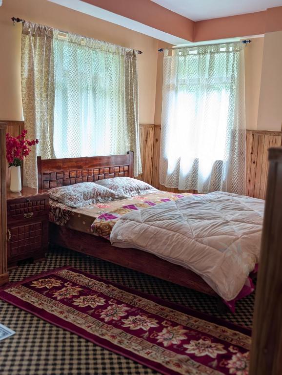 a bedroom with a large bed with curtains and a rug at Lepcha Homestay Darjeeling in Darjeeling