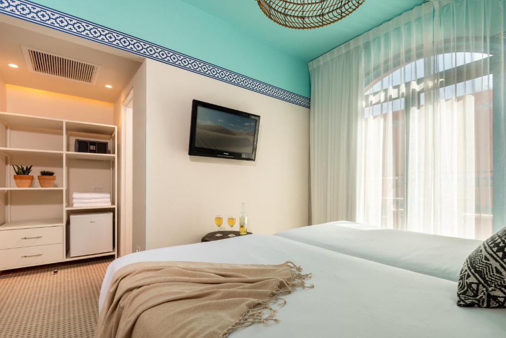 ein Schlafzimmer mit einem Bett und einem Fernseher an der Wand in der Unterkunft U Splash Resort Eilat in Eilat