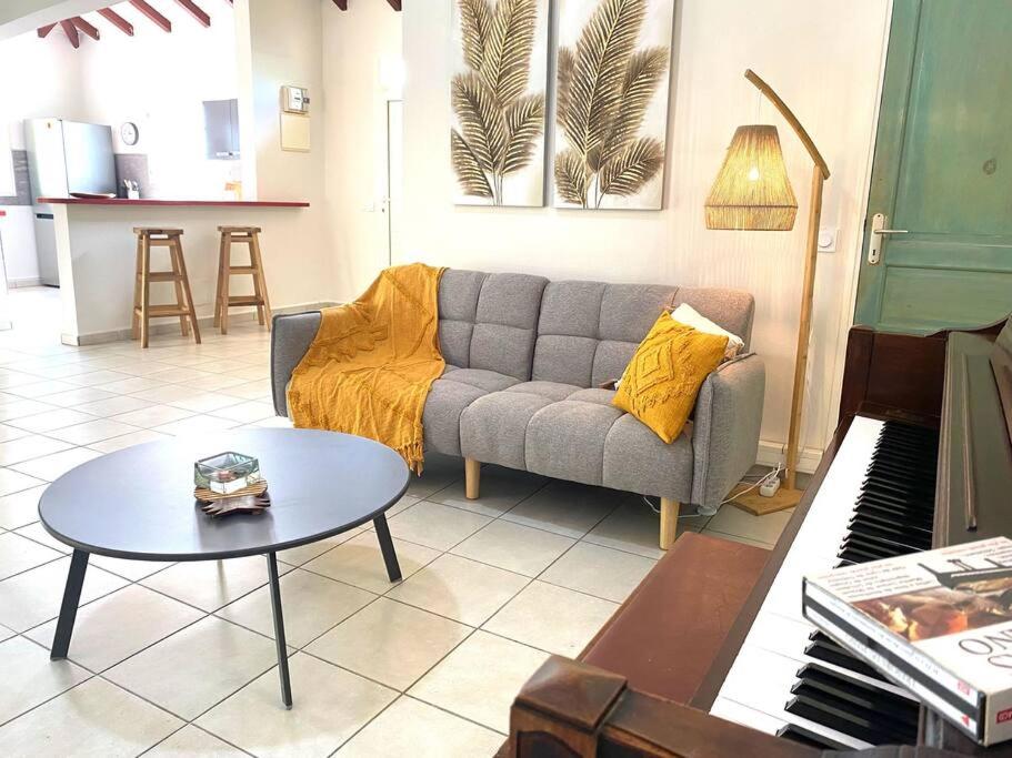 a living room with a couch and a table and a piano at Villa Oriane Élégance Créole à 4 min du CHU et 10 min de l'Aéroport in Les Abymes