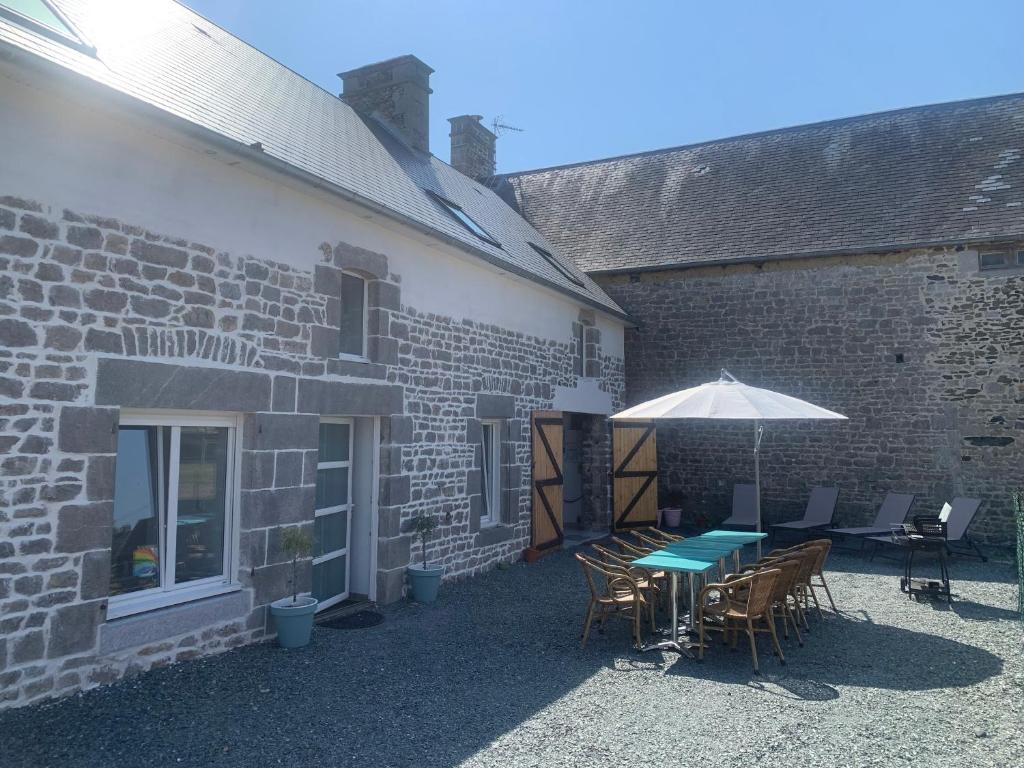 - une terrasse avec une table et un parasol à côté d'un bâtiment dans l'établissement Gite de groupe Les KerChouers, à Lingreville