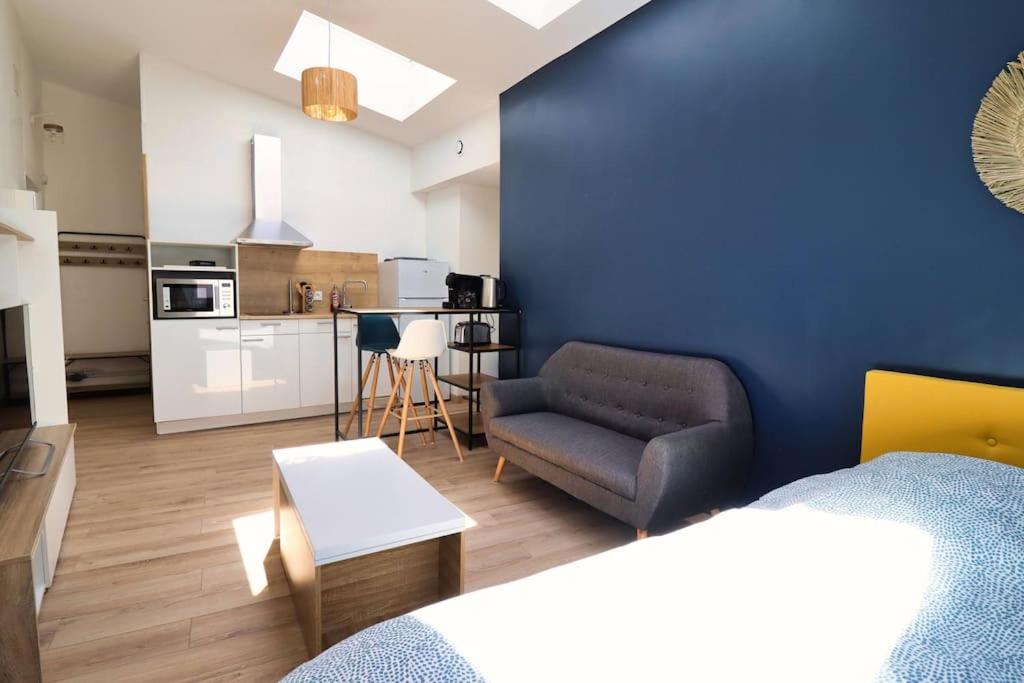 une chambre avec un mur bleu, un canapé et une cuisine dans l'établissement Bright and fully equipped studio, à Arras