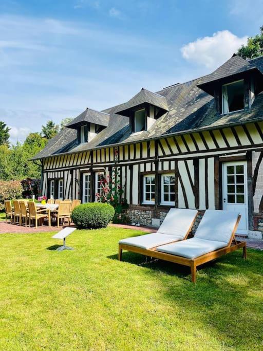 une maison avec une cour avec des chaises et un bâtiment dans l'établissement Splendide longère de charme - Collection Idylliq, à Conteville