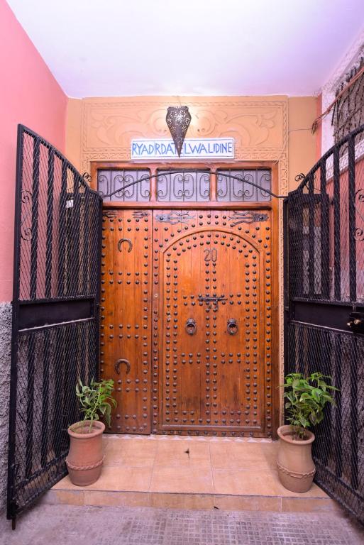 une porte en bois avec deux plantes en pot devant dans l'établissement RYAD RDATE LWALIDINE, à Marrakech