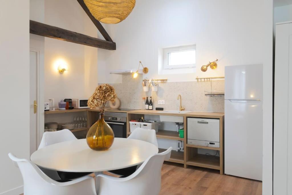 - une cuisine avec une table blanche et des chaises blanches dans l'établissement T3 cosy aux portes de Paris, à Saint-Denis