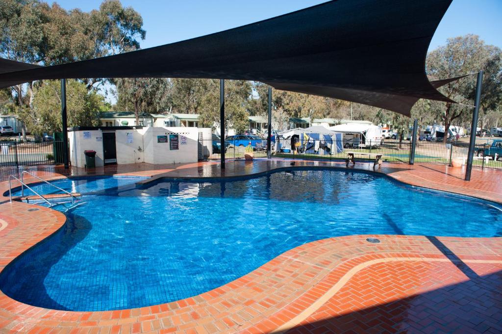 una gran piscina azul con sombrilla negra en NRMA Echuca Holiday Park, en Echuca