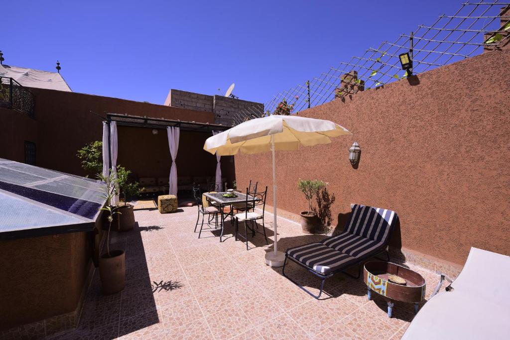 une terrasse avec une chaise, un parasol et une table dans l'établissement RYAD RDATE LWALIDINE, à Marrakech