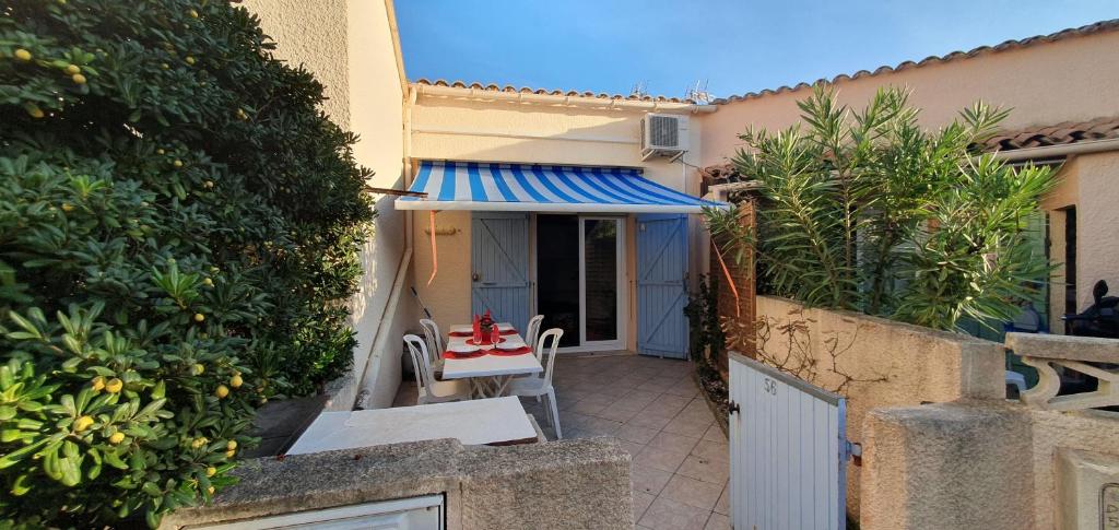 une terrasse avec une table et des chaises dans une maison dans l'établissement L'Azur - Maison avec terrasse proche plage, au Barcarès