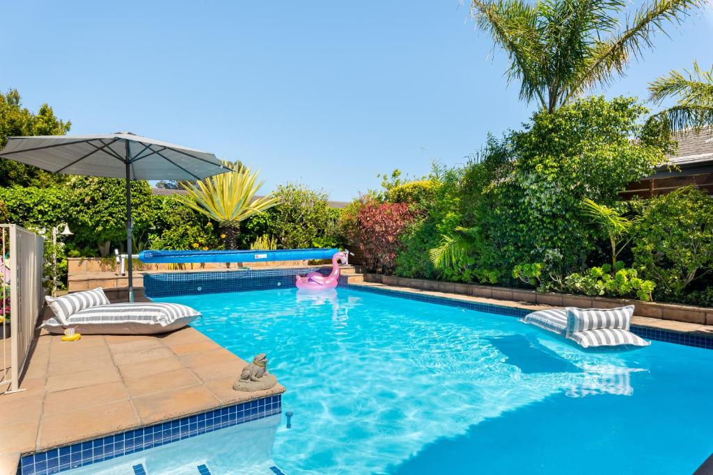 una piscina con terrazza e ombrellone di Meerendal Cottage-Affordable Luxury-Private Garden with Pool & Hot Tub a Città del Capo