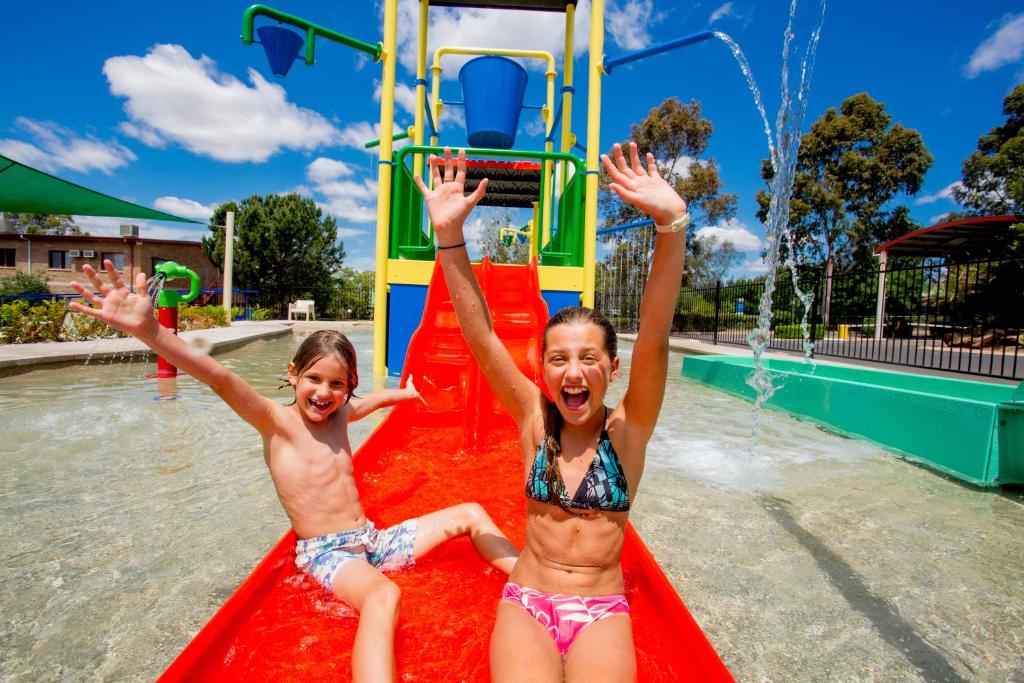 two girls are playing in a pool on a sunny day at Discovery Parks - Dubbo in Dubbo