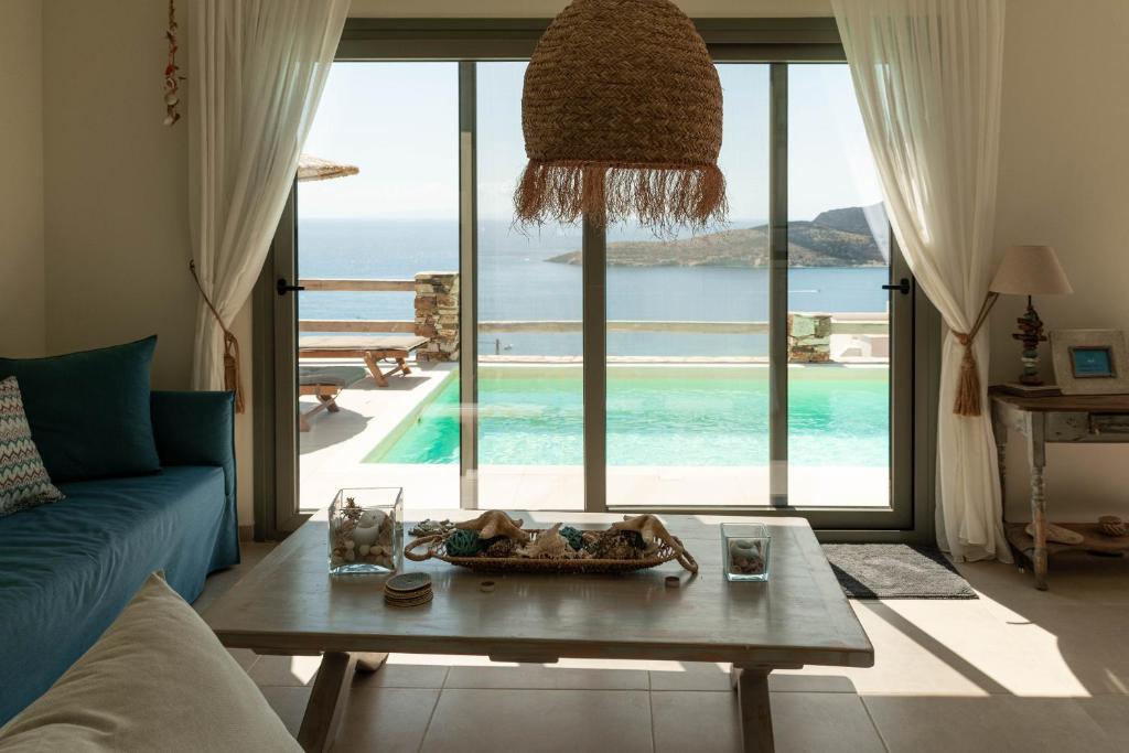 a living room with a table and a view of the ocean at Deja Blue Villa 1 in Agios Georgios