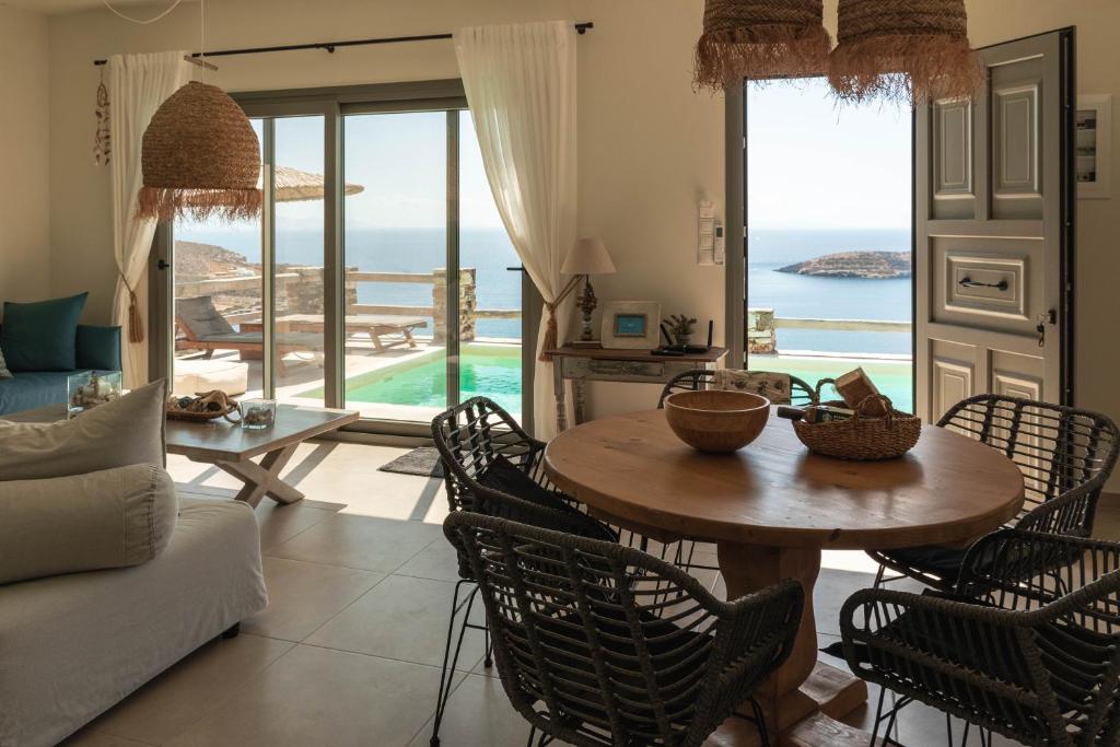 a living room with a table and chairs and the ocean at Deja Blue Villa 1 in Agios Georgios