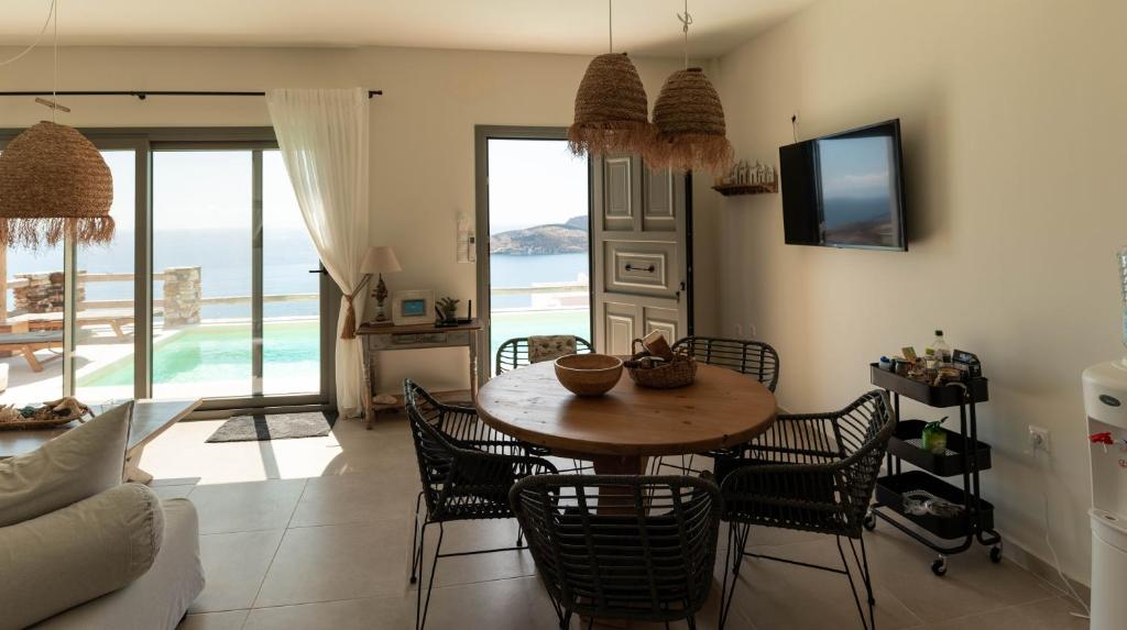 a dining room with a table and chairs with a view of the ocean at Deja Blue Villa 1 in Agios Georgios