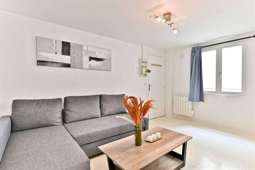 un salon avec un canapé gris et une table dans l'établissement Appartement proche Canal Saint Martin - II, à Paris