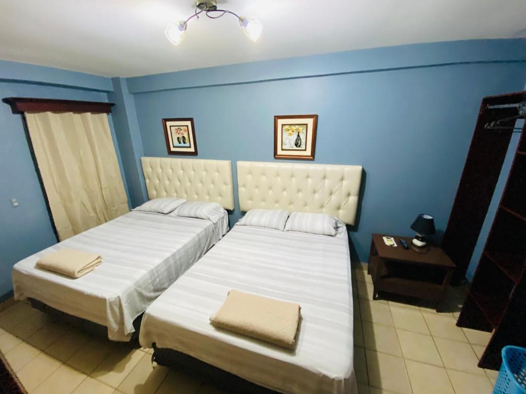 圣佩德罗苏拉Merendon Suite Apartamento的一间蓝色墙壁的房间里有两张床