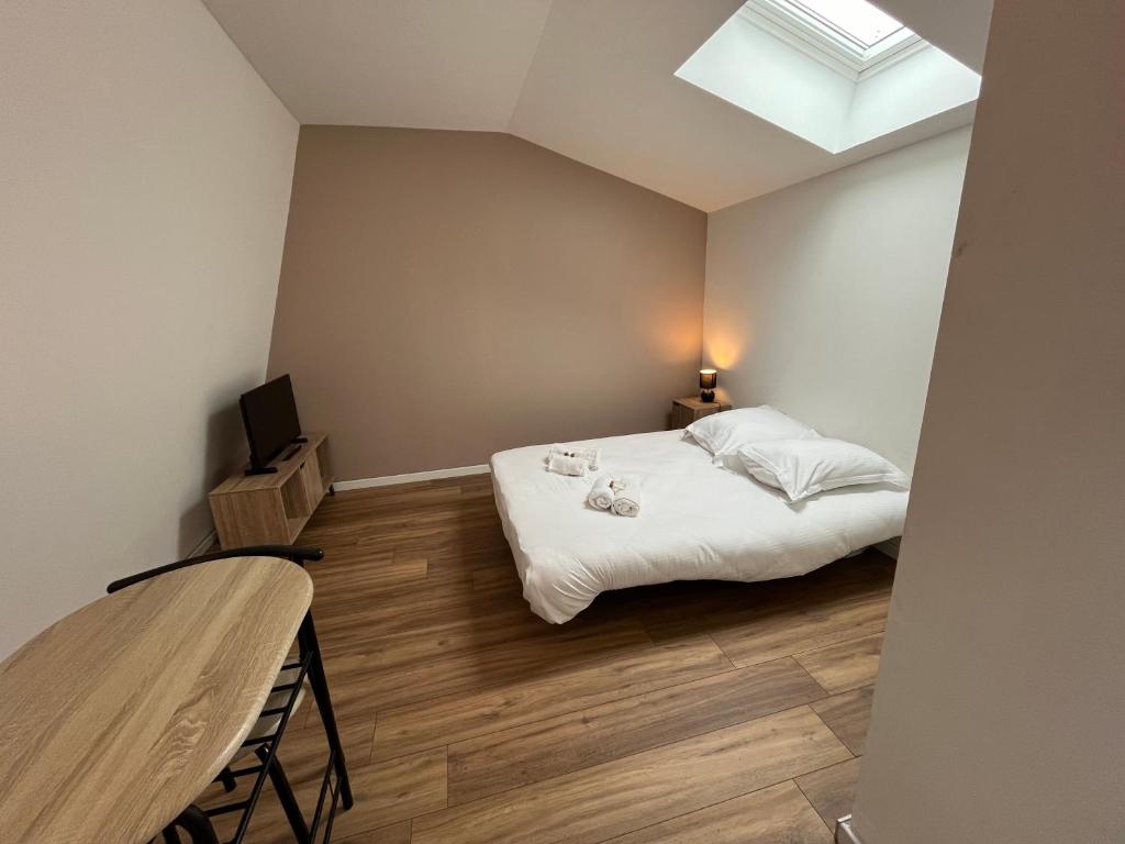 - une chambre avec un lit, une table et une lucarne dans l'établissement Créma, Studio proche centre ville, à Caen