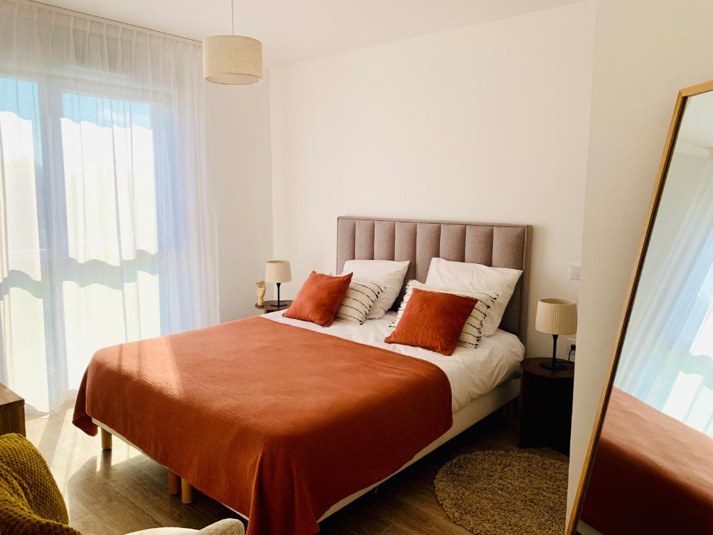 een slaapkamer met een bed met oranje en witte kussens bij DOMITYS - Le Bouquet in Charnay-lès-Mâcon