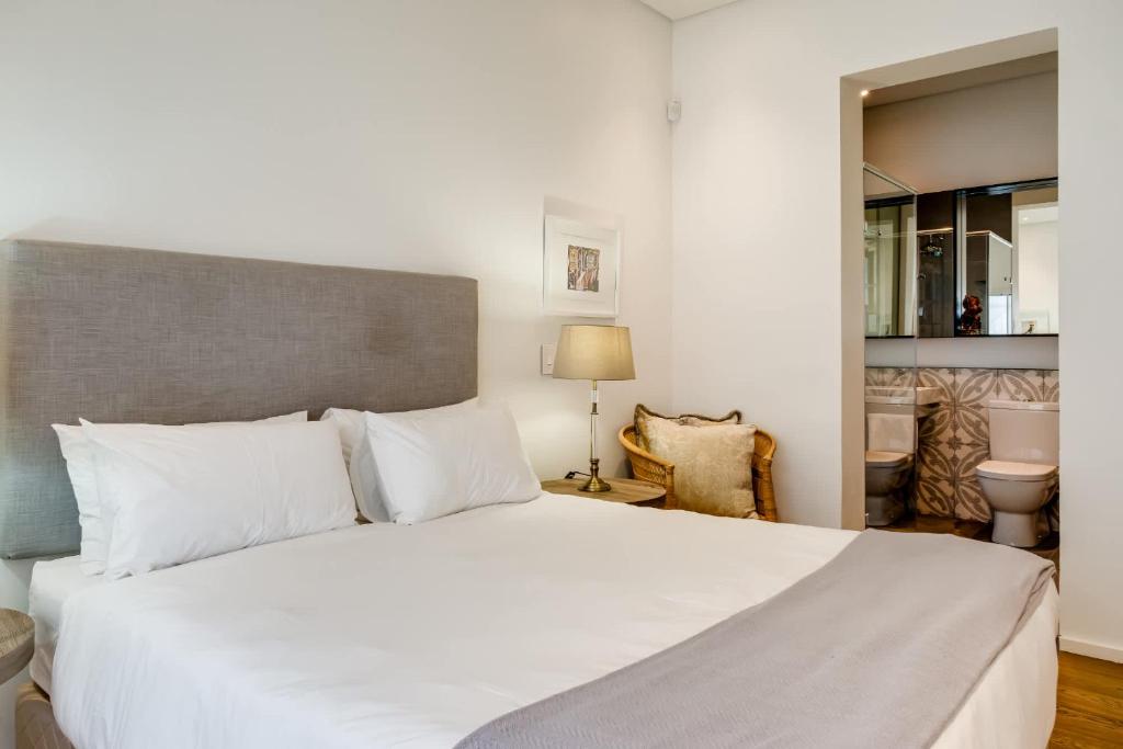 a bedroom with a large white bed and a bathroom at Ocean Vue in Cape Town