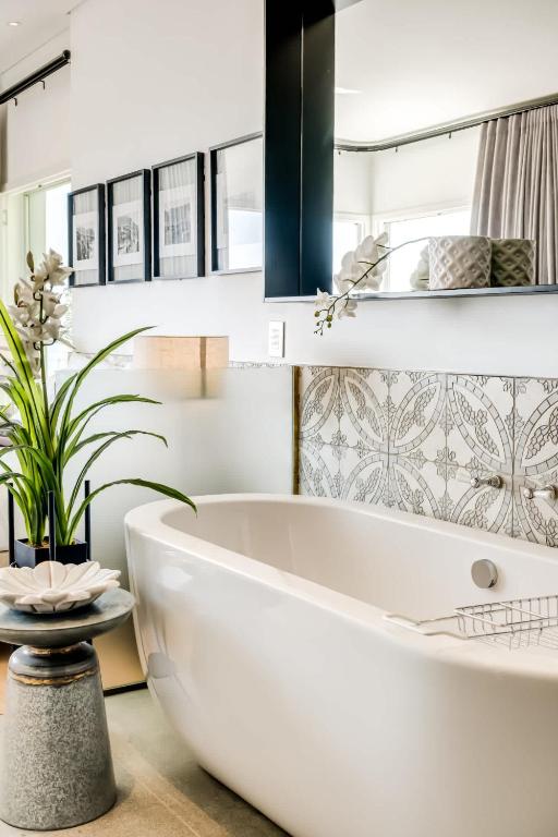 a white bathroom with a tub and a plant at Ocean Vue in Cape Town