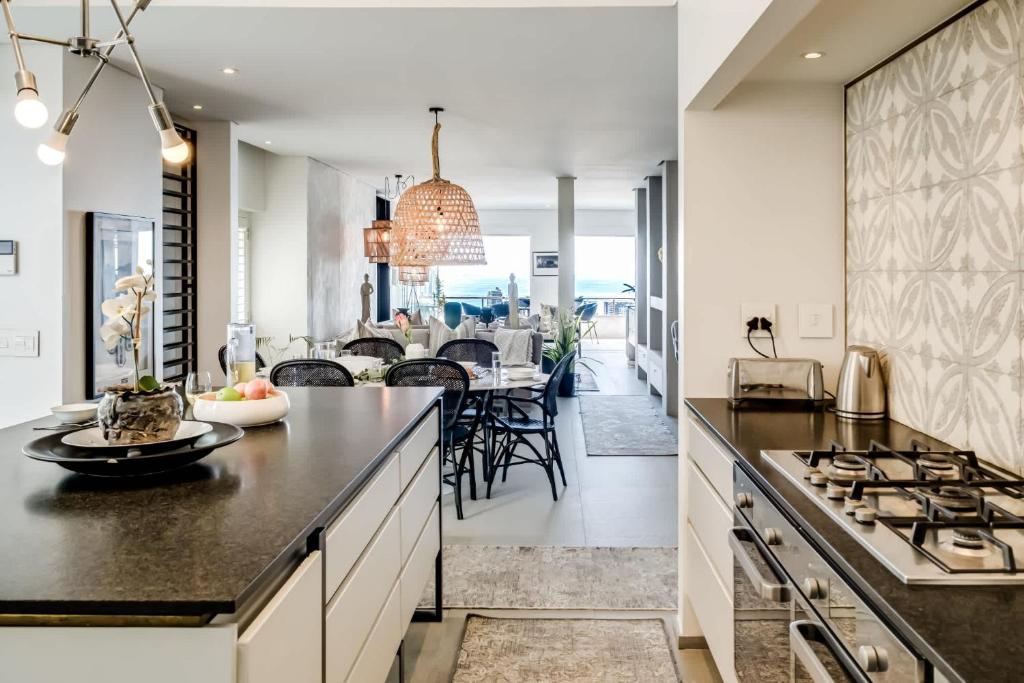 a kitchen and dining room with a dining table in the distance at Ocean Vue in Cape Town