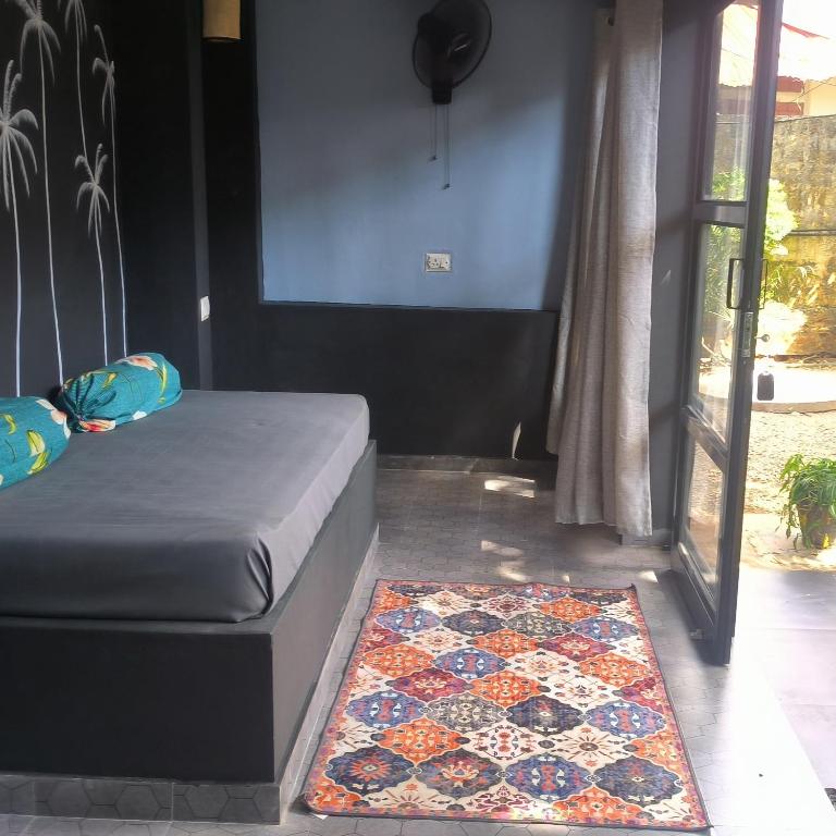 a bedroom with a bed and a rug on the floor at Mad about Coco Yoga & Beach Retreat in Varkala