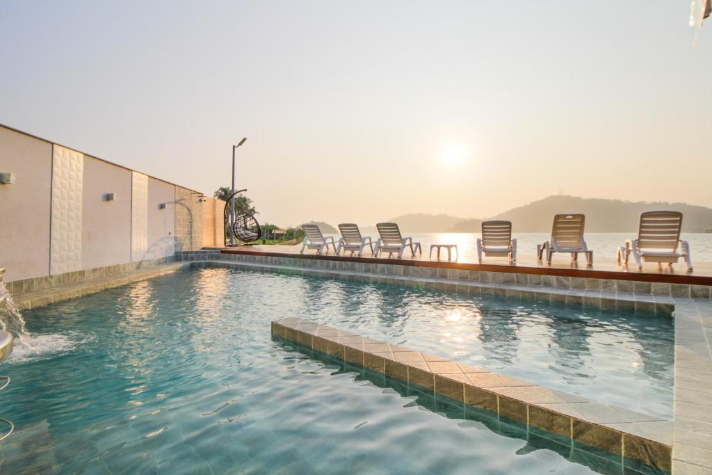 a pool with chairs sitting on the side of a building at VELINN Pousada Angra Sunset in Angra dos Reis