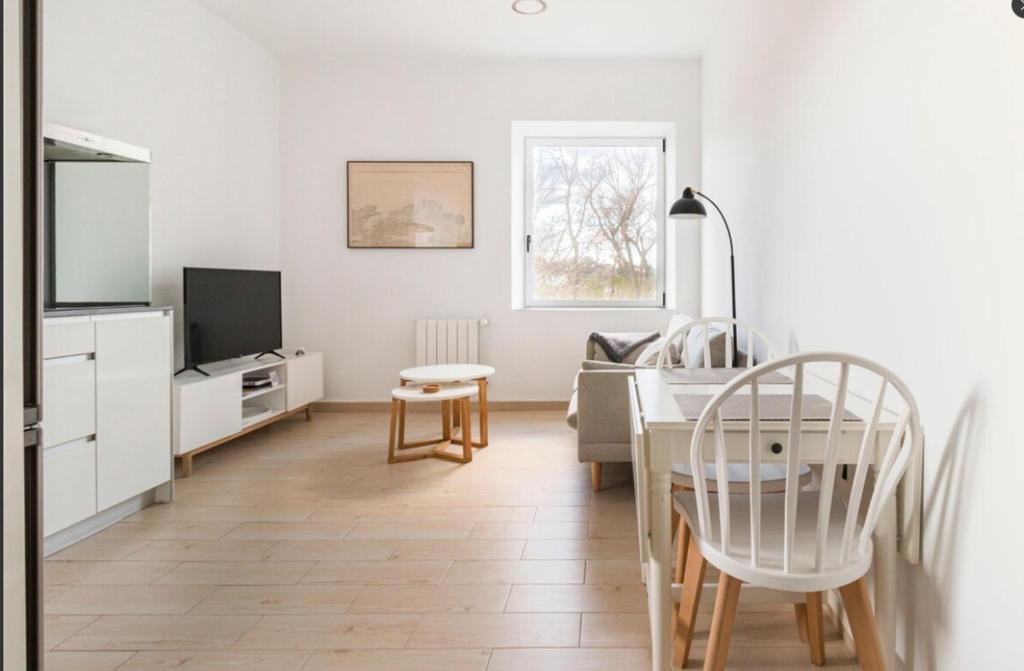 a white living room with a table and a tv at Apartamento con vistas a la playa in Santander