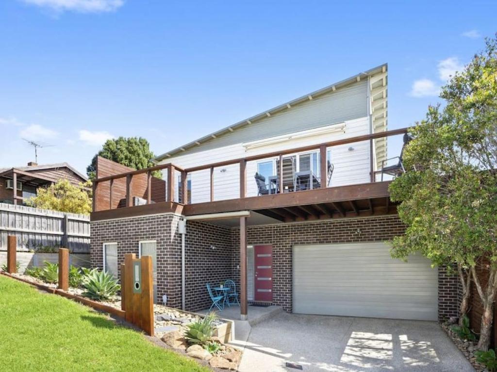 een stenen huis met een balkon en een garage bij Oceans 10 in Ocean Grove