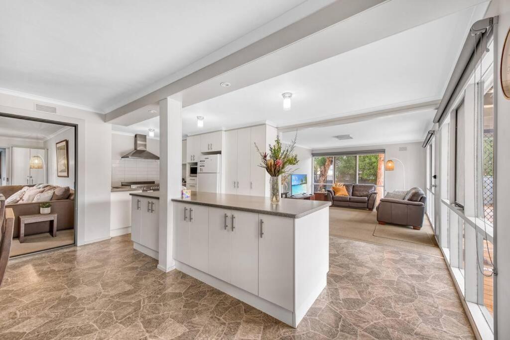 Una cocina con gabinetes blancos y una sala de estar. en Family Moments, en Anglesea