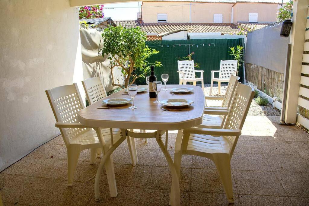 - une table en bois avec des chaises et une bouteille de vin dans l'établissement Charmante maison proche plage, à Saint-Cyprien
