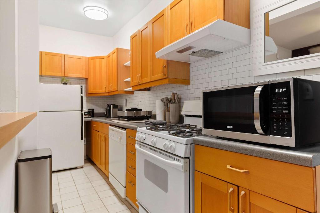 a kitchen with white appliances and wooden cabinets at Chic 1-BR Loft Nestled Between Dupont & Logan in Washington, D.C.