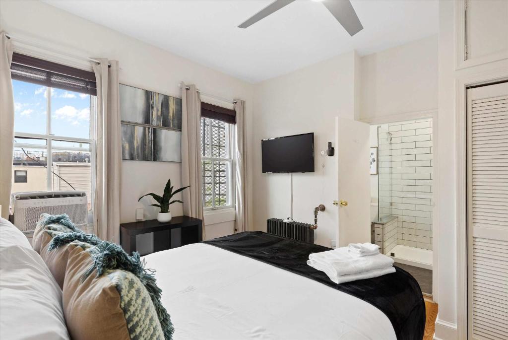 a white bedroom with a bed and a tv at Chic 1-BR Loft Nestled Between Dupont & Logan in Washington, D.C.