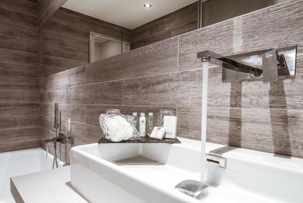 a bathroom with a sink and a bath tub at Hôtel Le White - Le 42 Restaurant in Champéry