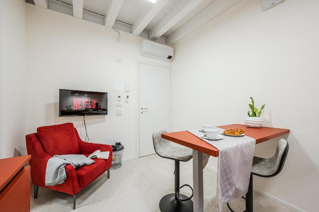 a living room with a red chair and a table at Loft Il Moro 2 Maranello Sassuolo Free Netflix & wi-fi in Casalgrande