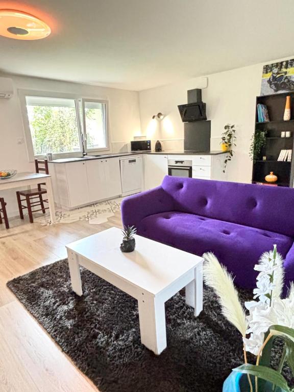 un salon avec un canapé violet et une table dans l'établissement Le Charmant T3 avec Jardin Privé, à Flourens