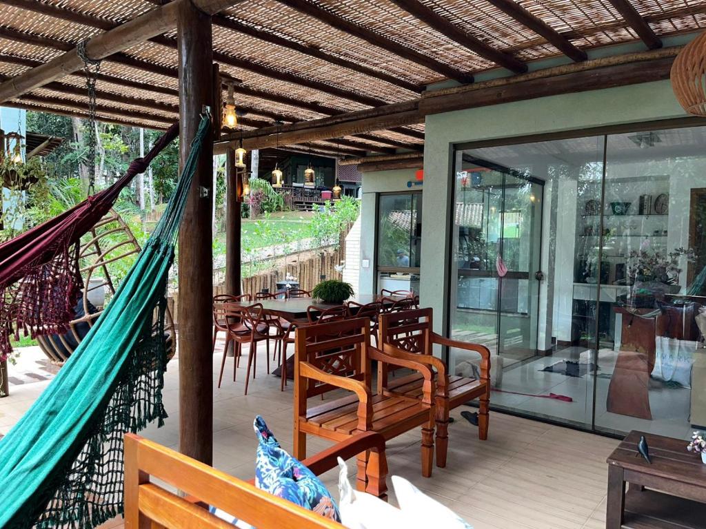 a hammock on a patio with a table and chairs at CASA PRAIA DO FORTE in Mata de Sao Joao