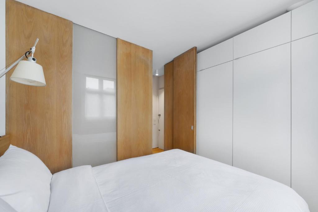 a bedroom with a white bed and wooden walls at Crawford Street Apartment By Morethanstays in London