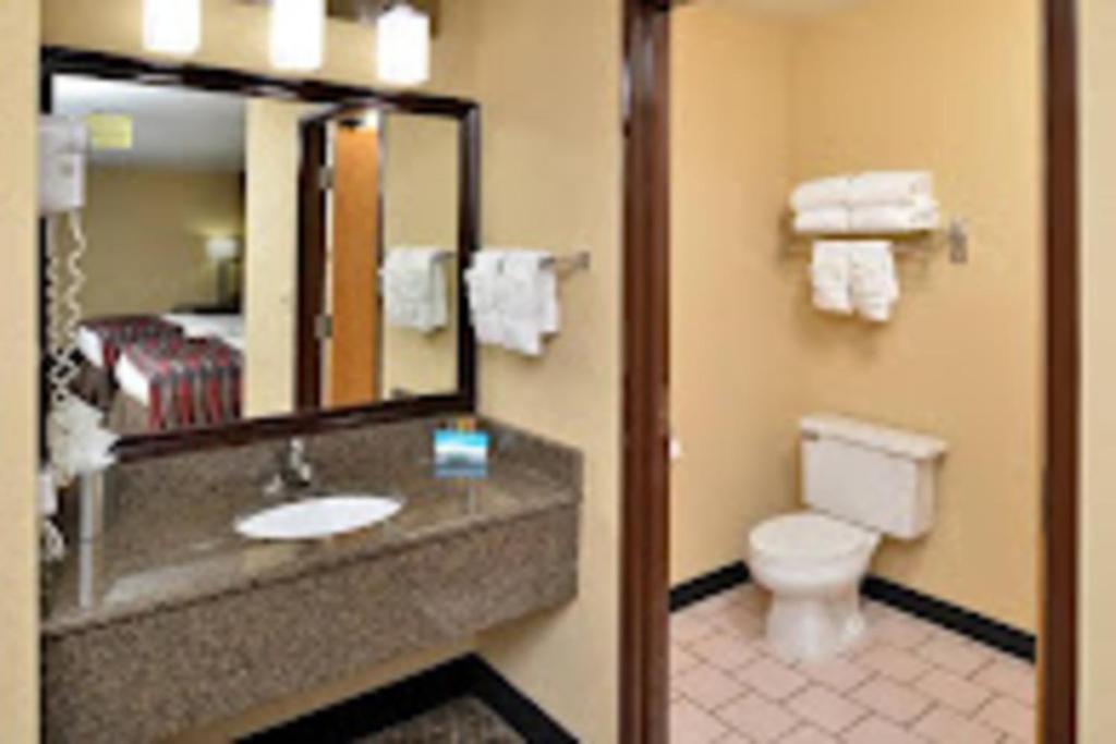 a bathroom with a sink and a toilet and a mirror at Baymont by Wyndham Ardmore I-35 in Ardmore