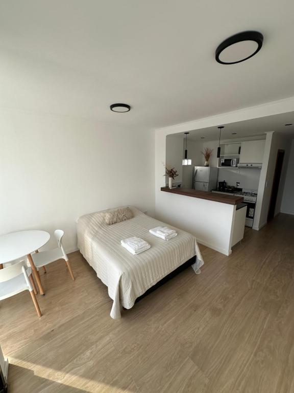 a white bedroom with a bed and a table at Departamento super luminoso - Zona 12 y 38 in La Plata