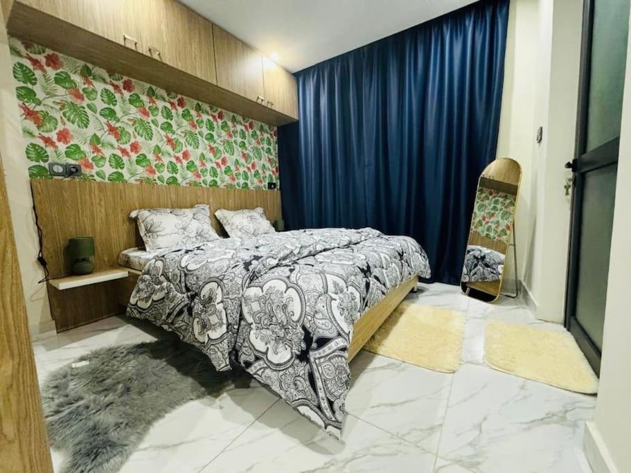 ein Schlafzimmer mit einem Bett und einem blauen Vorhang in der Unterkunft Appart haut standing Riviera in Abidjan