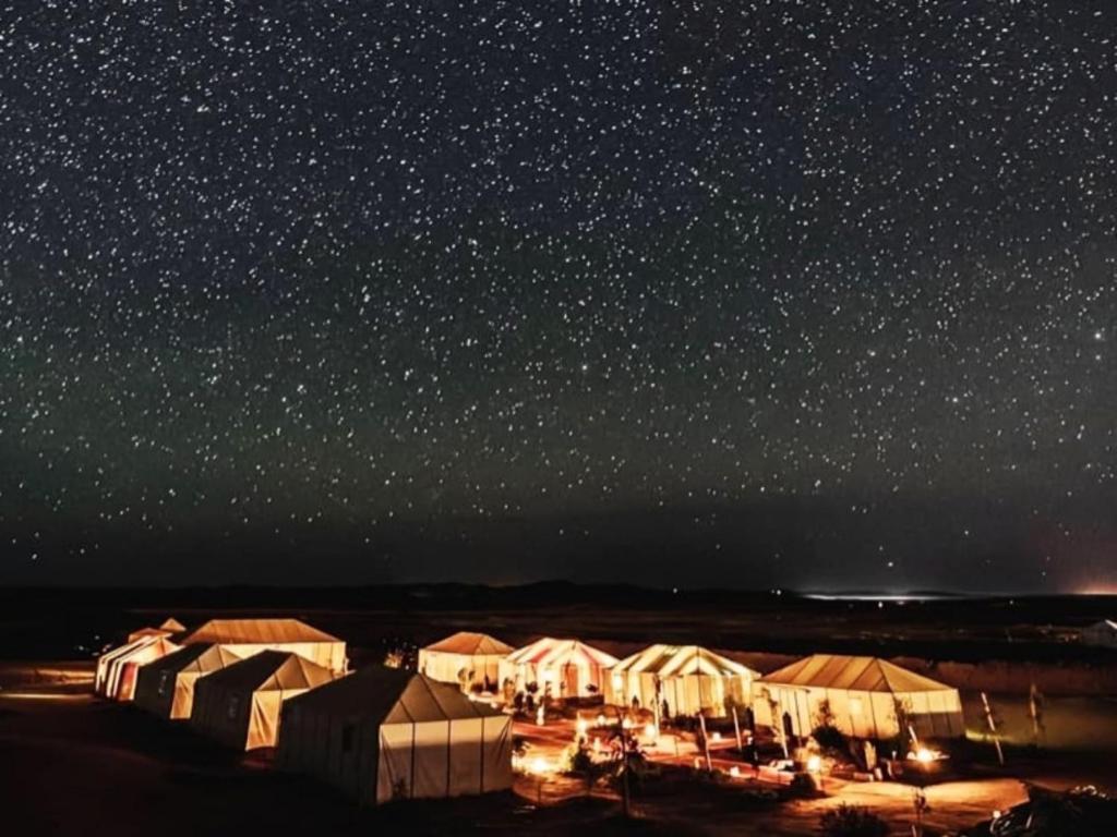 a group of tents under a starry sky at night at Exceptional Luxury Camp in Merzouga