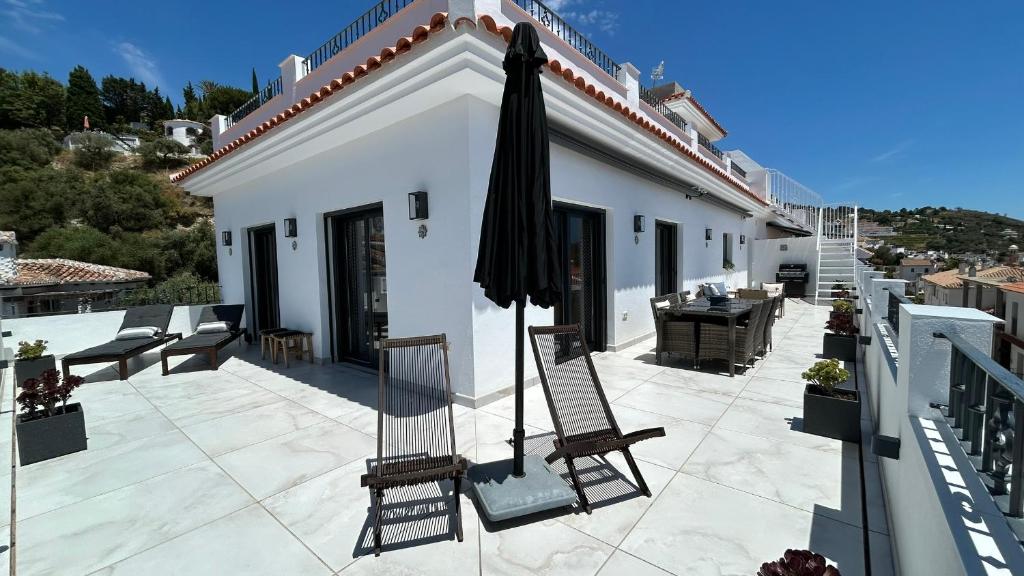 eine Terrasse mit Sonnenschirm und Stühlen auf einem Gebäude in der Unterkunft Comino Penthouse in Cómpeta