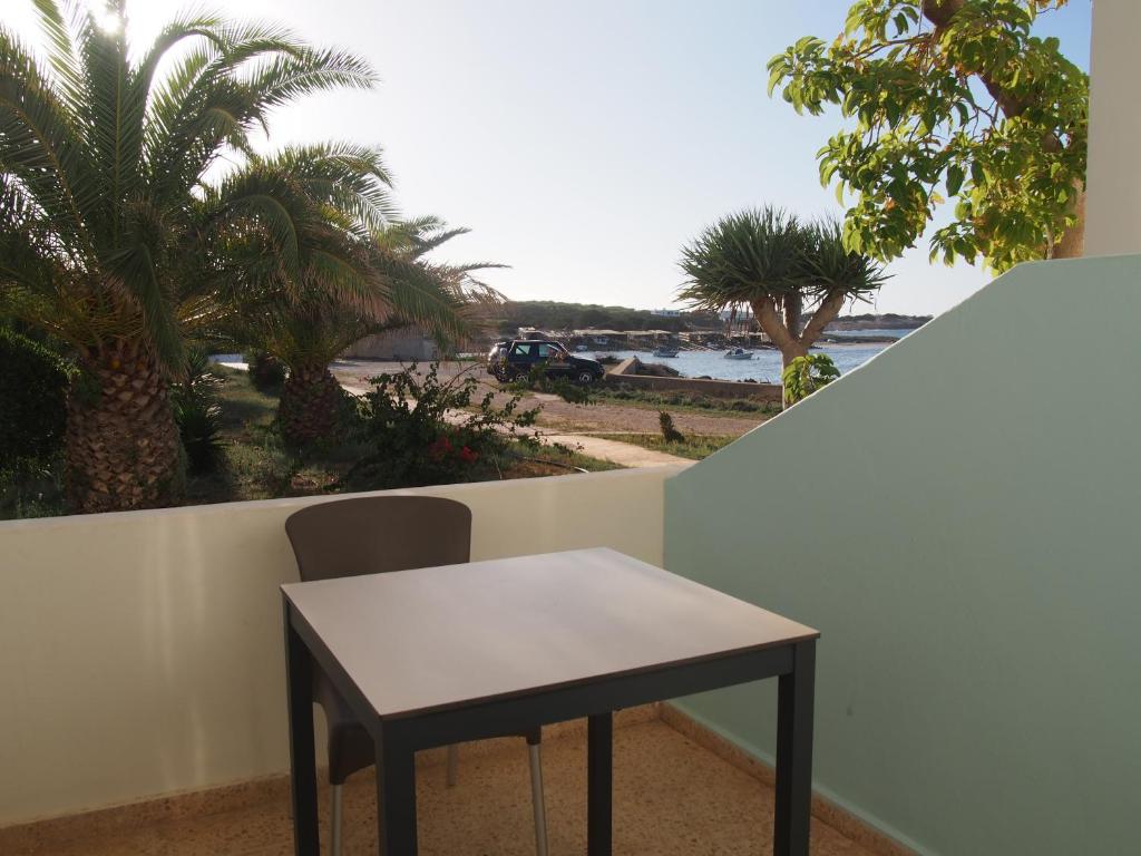 a table and a chair on a balcony with palm trees at Hotel Roca Bella in Es Pujols