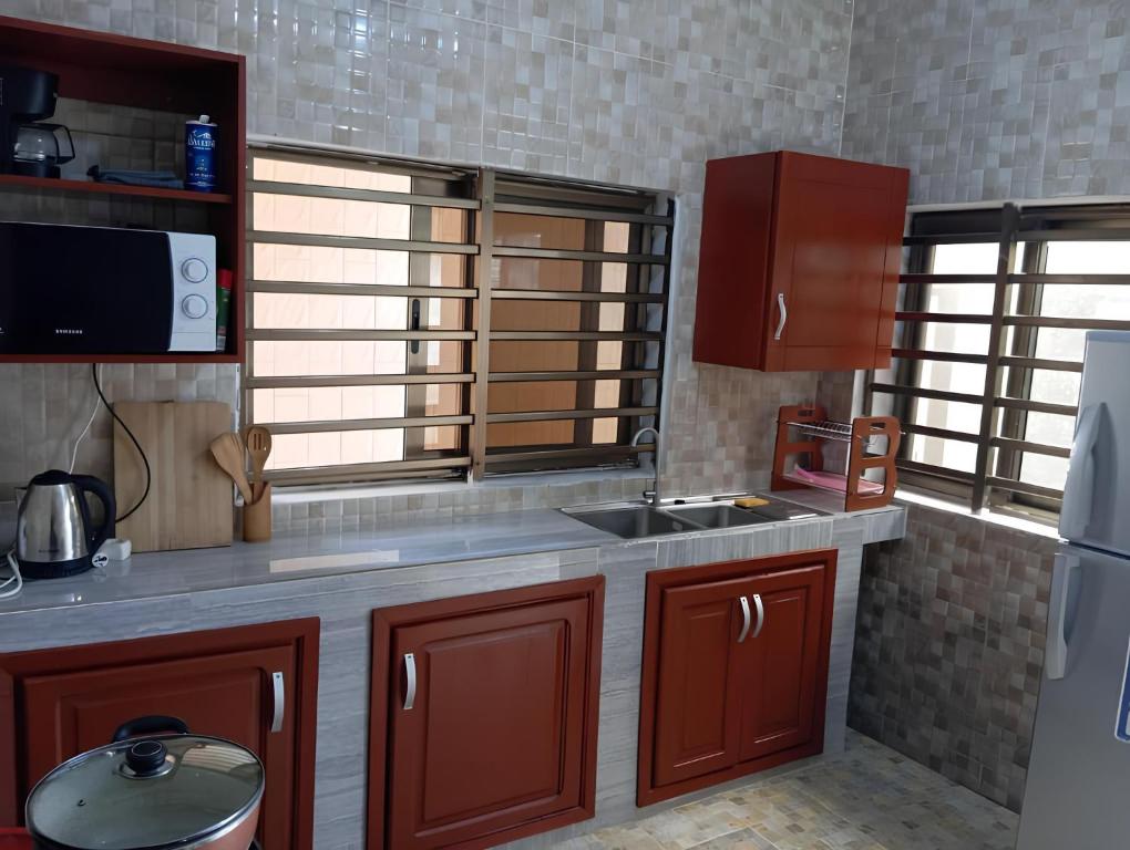 a kitchen with brown cabinets and a sink and a refrigerator at Magnifique Maison de ville Bord de mer Cotonou Fidrjossè in Cotonou