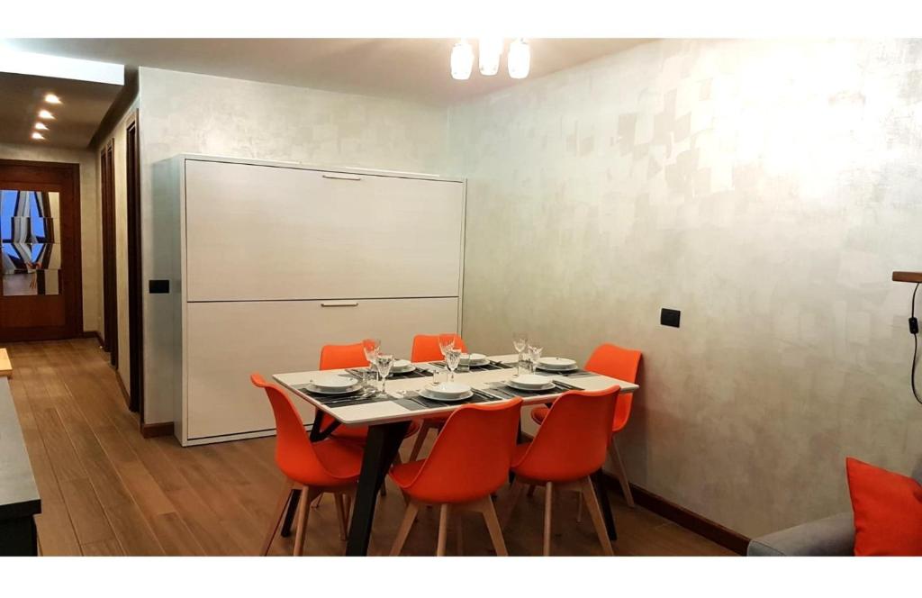jadalnia ze stołem z pomarańczowymi krzesłami i tablicą w obiekcie Orange Fox Cervinia apartment Vda Vacanze in Vetta CIR 0185 w mieście Breuil-Cervinia