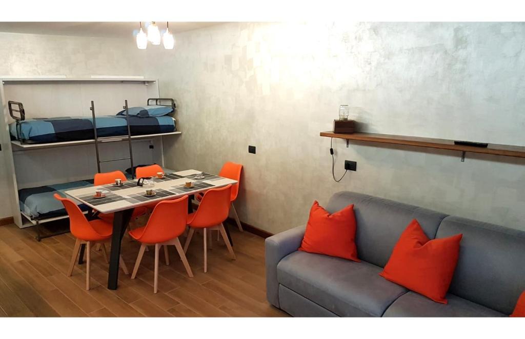 Pokój z kanapą i stołem z pomarańczowymi krzesłami w obiekcie Orange Fox Cervinia apartment Vda Vacanze in Vetta CIR 0185 w mieście Breuil-Cervinia