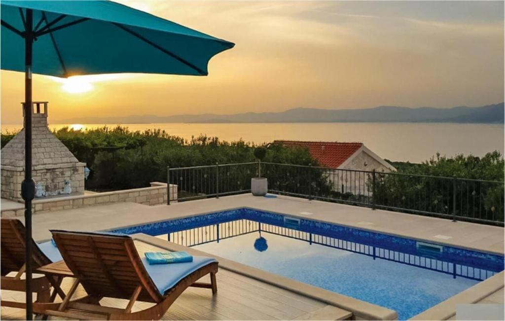 a pool with chairs and an umbrella on a deck at House Ita in Postira