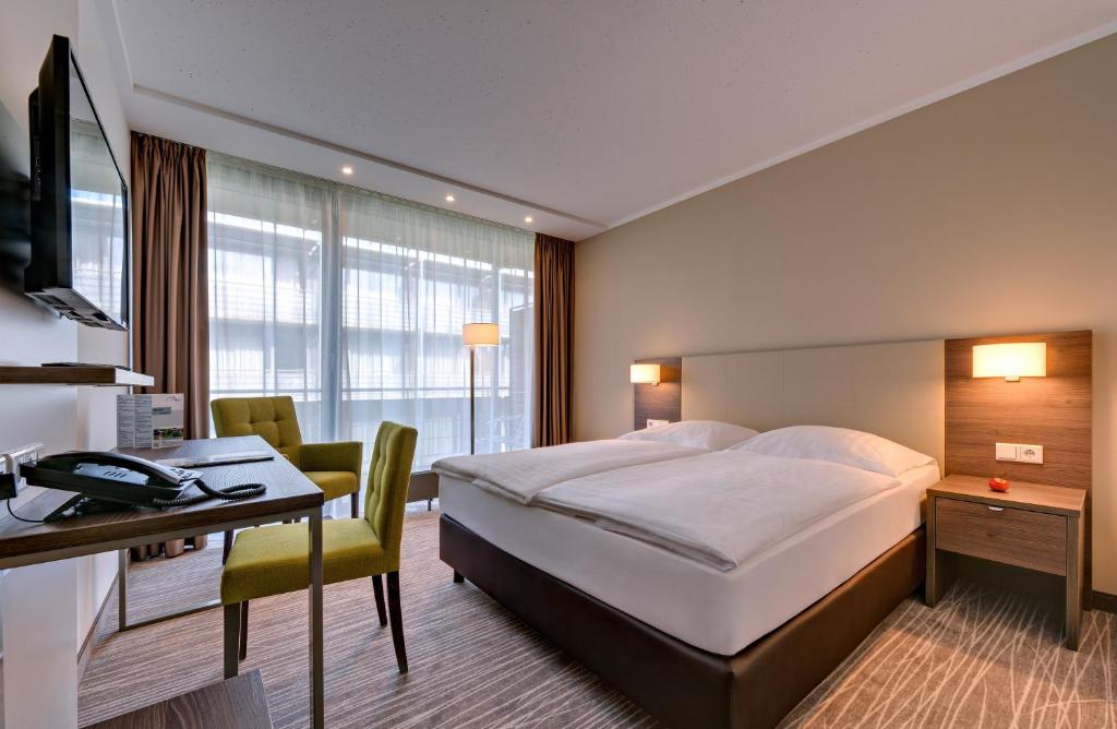 a hotel room with a bed and a desk and a computer at GenoHotel Baunatal in Baunatal